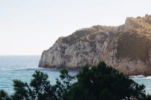 a rocky cliff next to a body of water